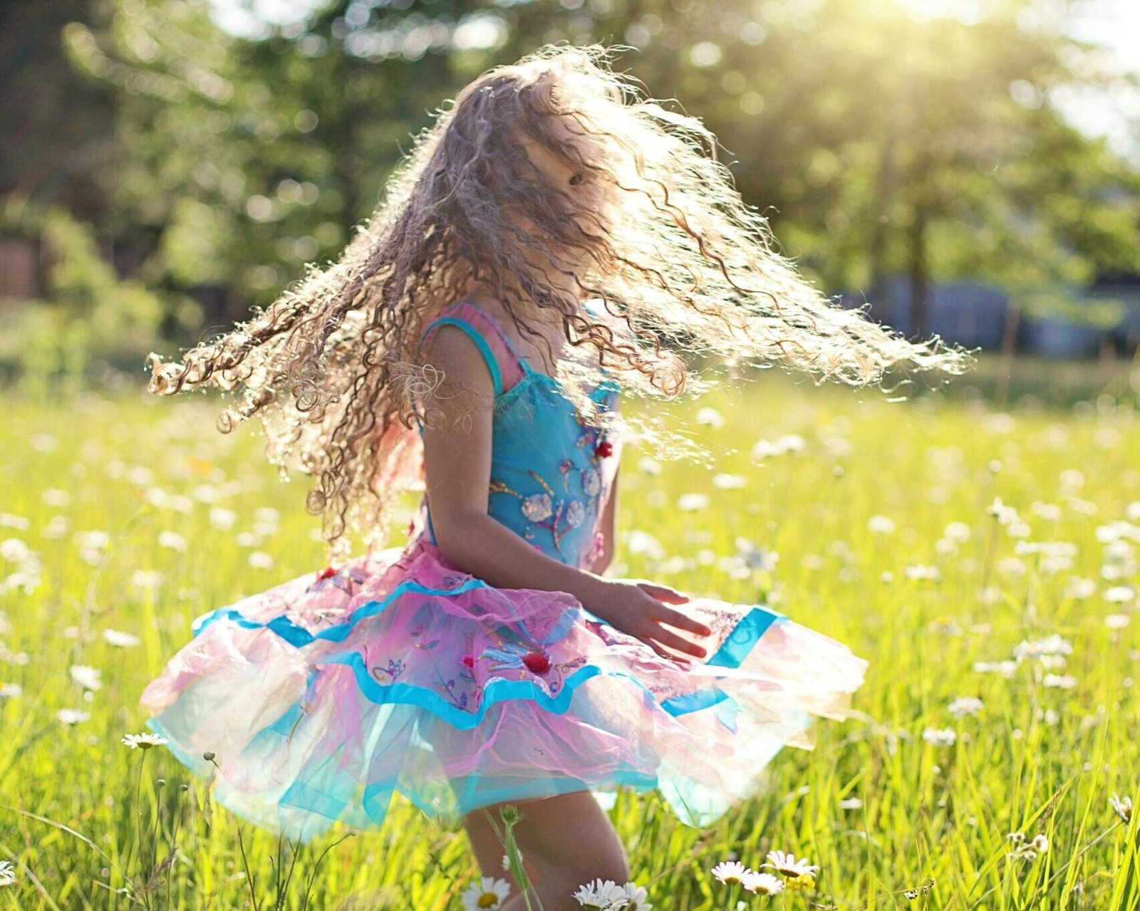 A carefree young girl dancing in a sunlit meadow filled with daisies.